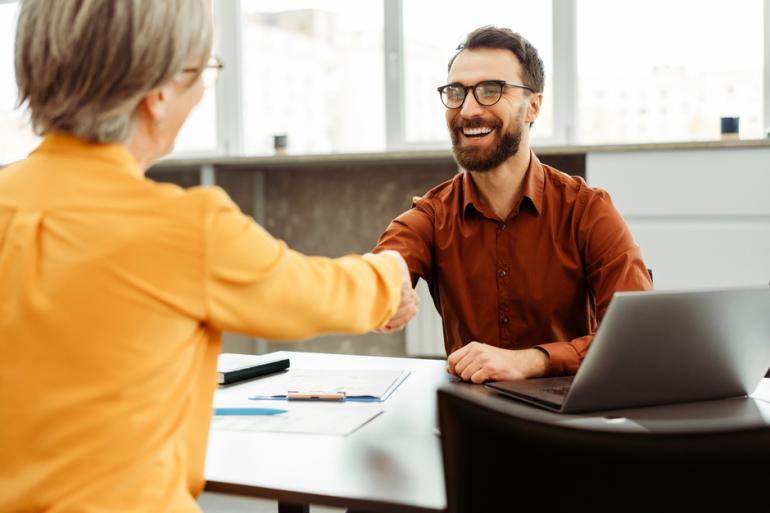 Dos personas en una entrevista dándose la mano